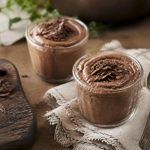 Mousse au chocolat de grand-mère servie en verrines, parsemée de copeaux de chocolat noir, sur une table en bois rustique