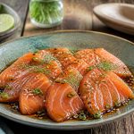 Pavés de saumon mariné à la sauce soja et au miel, caramélisés à la poêle, parsemés de graines de sésame noir et de cébette, servis sur riz japonais