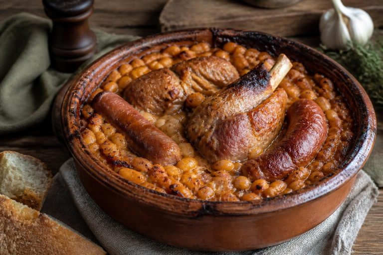 Cassoulet maison façon grand-mère dans une cassole en terre cuite, avec haricots tarbais, confit de canard et saucisse de Toulouse, croûte dorée sur le dessus